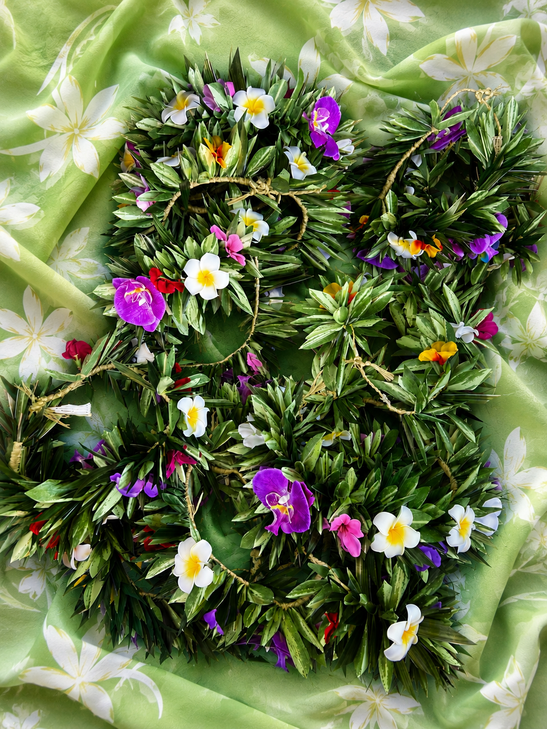 Couronnes de fleurs polynésiennes et feuillages tressés sur tissu vert